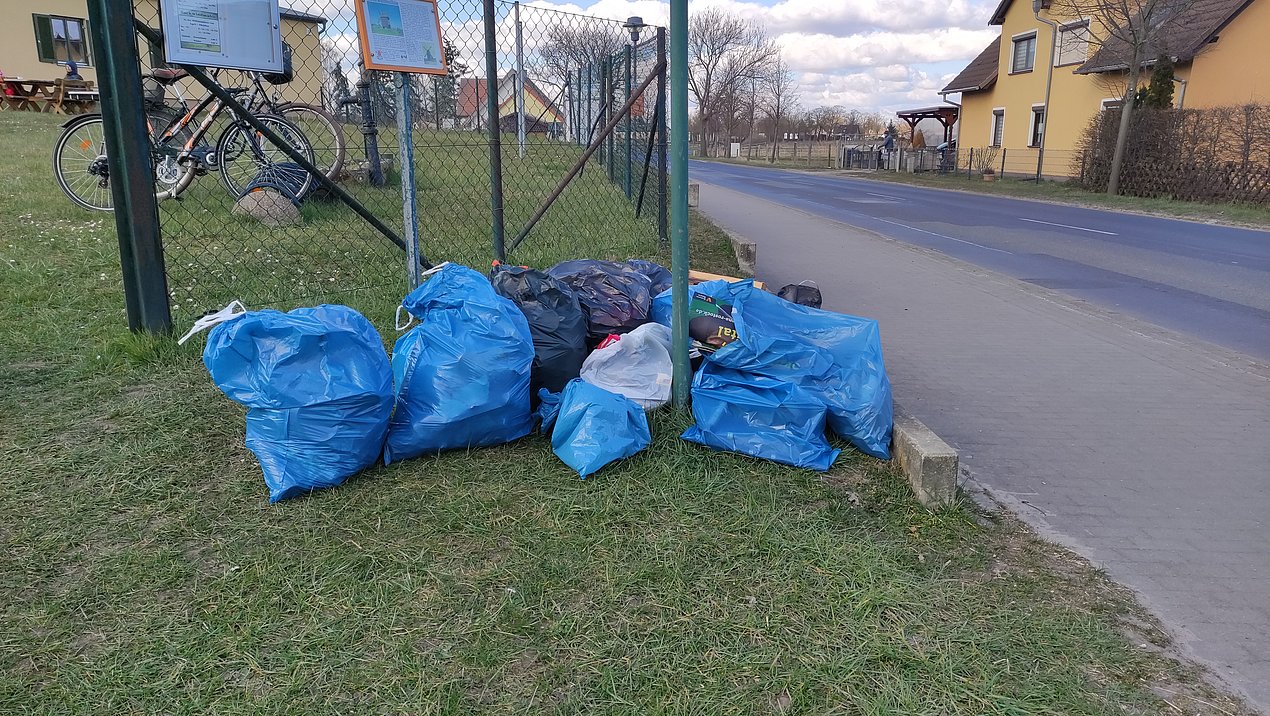 Gesammelter Müll in Säcken, die vor dem Zaun des Areals der Bockwindmühle und der Bürger- und Tourismusinformation liegen.